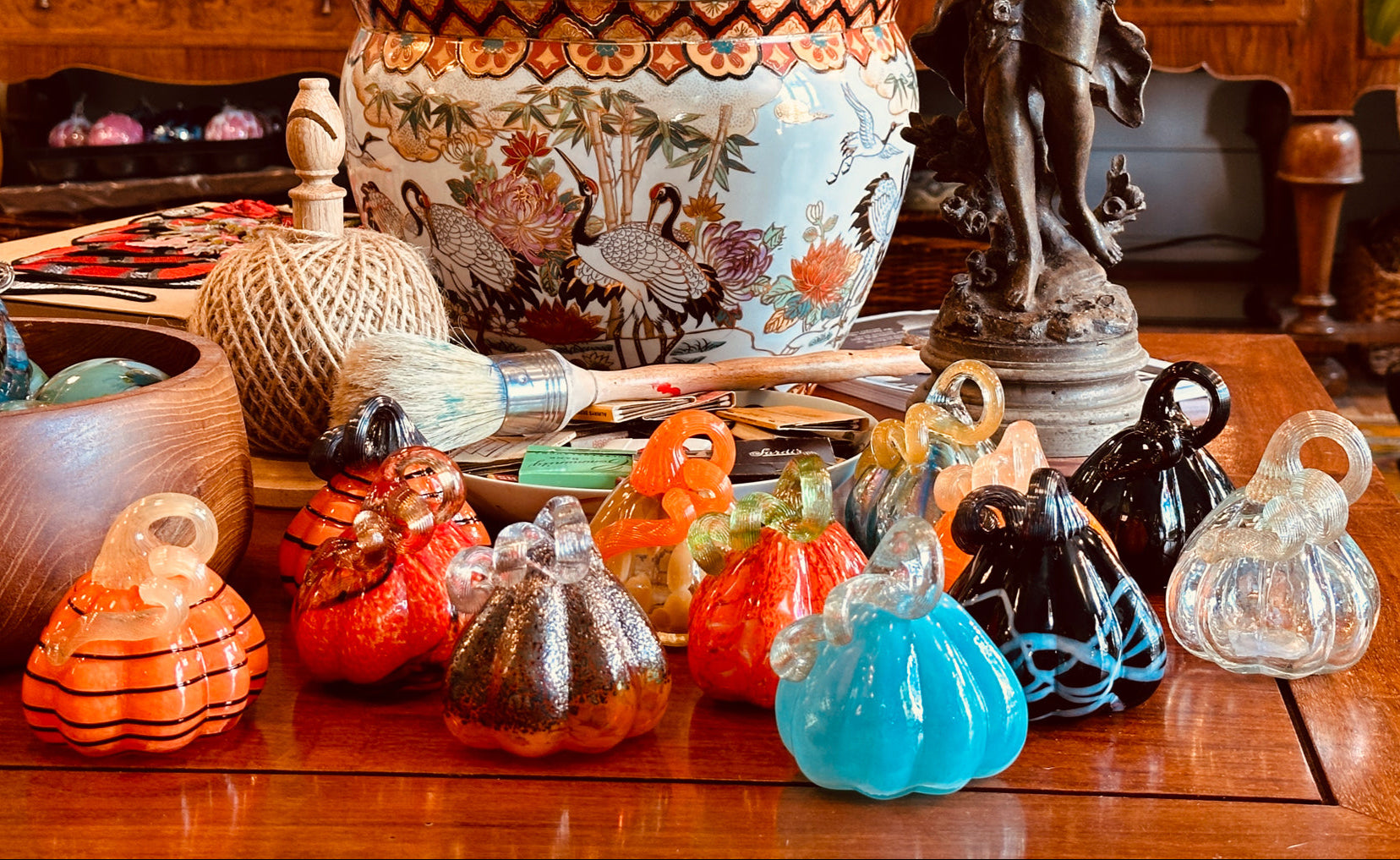 Colorful glass pumpkins on a wooden table with decorative items in the background