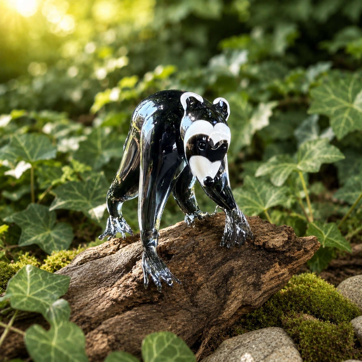 Jimothy Figurine, a glass figurine of a black and white raccoon on a wooden log surrounded by greenery.
