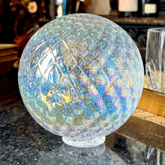 Alki Diamond Facet Float reflecting sunlight with colorful facets on a dark countertop.
